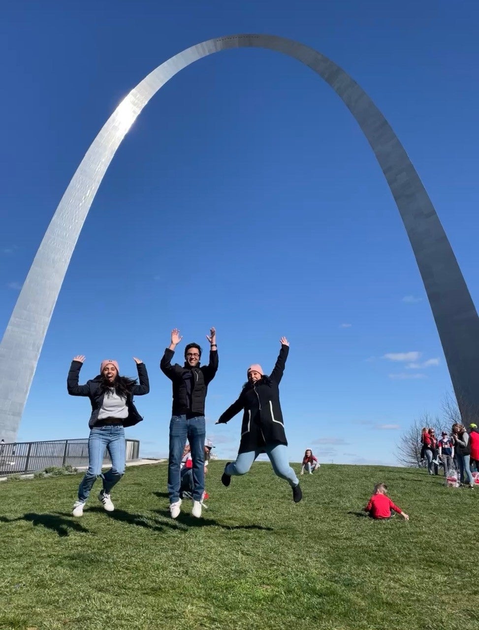 students leap into the air underneath arch in St. Louis