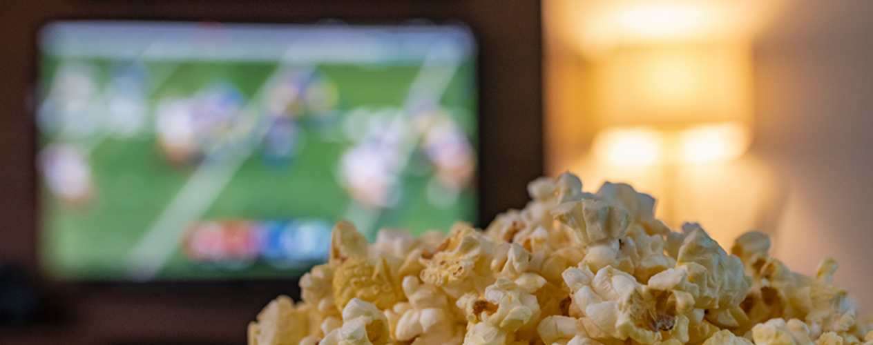 Bowl of popcorn in front of TV playing football