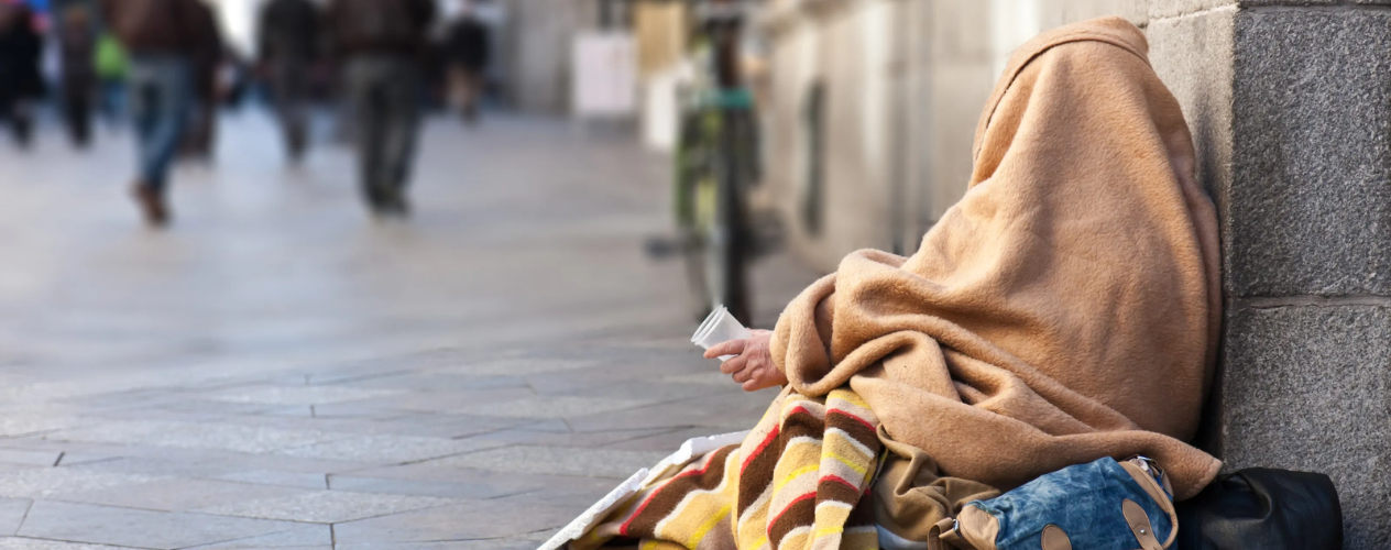 Unhoused individual wrapped in blankets