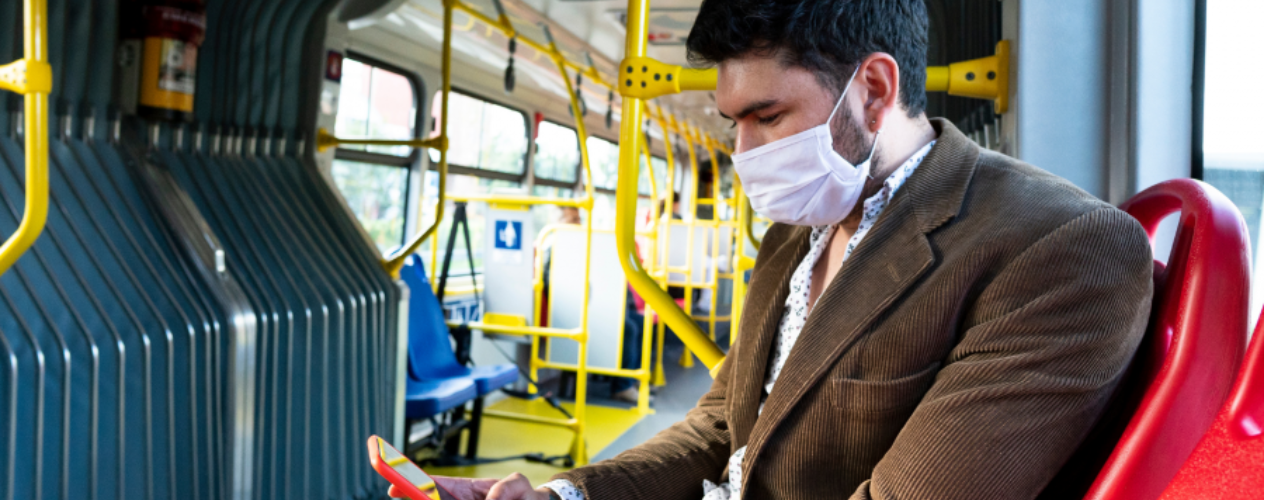 Man in mask on subway looking at phone