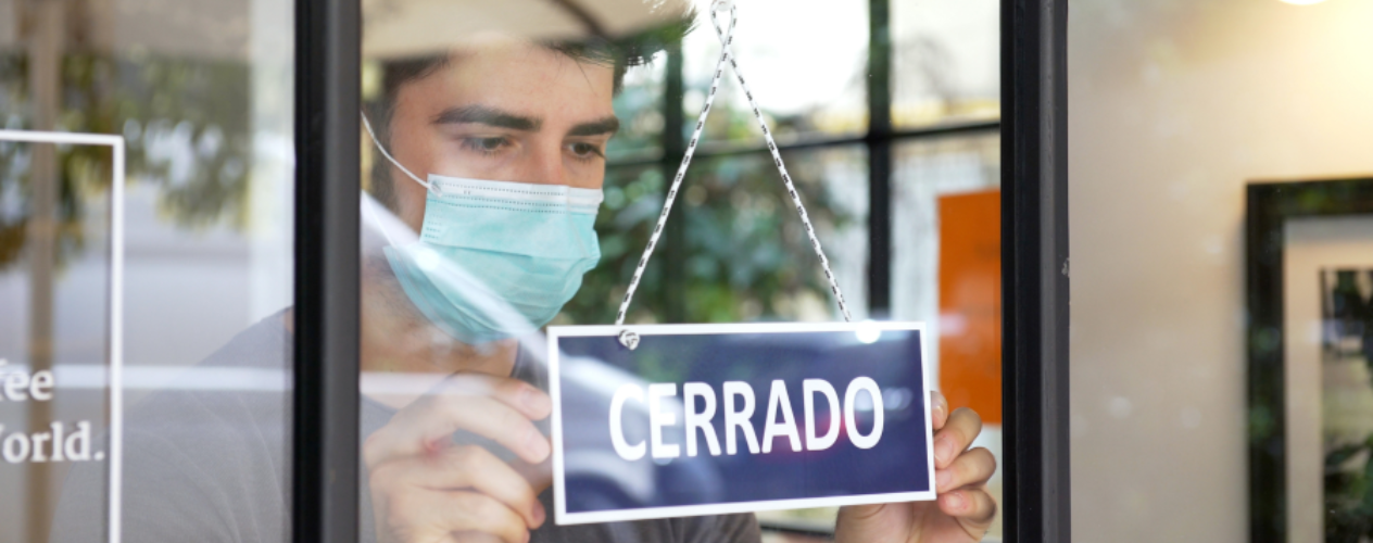Person closing a store with a "CERRADO" sign