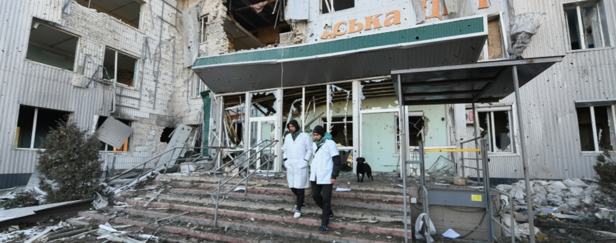 Two workers walking out of a damaged hospital in Ukraine