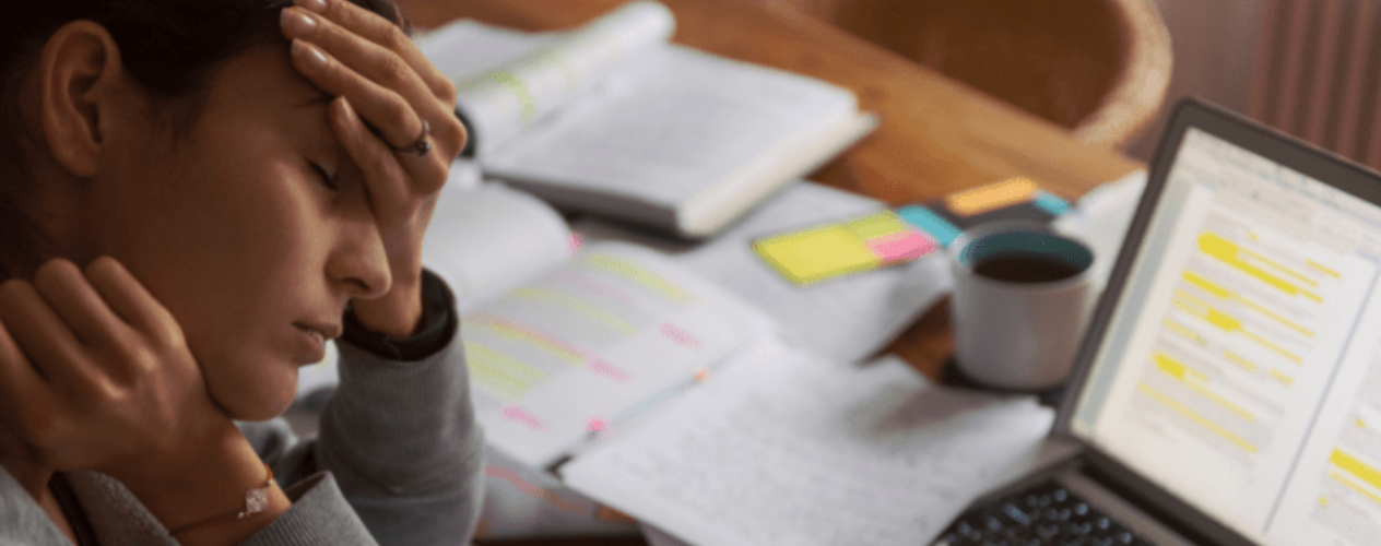 Stressed individual looking at paperwork and computer