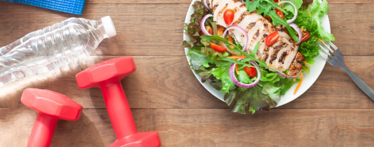 Water bottle, two hand weights, and a plate of salad