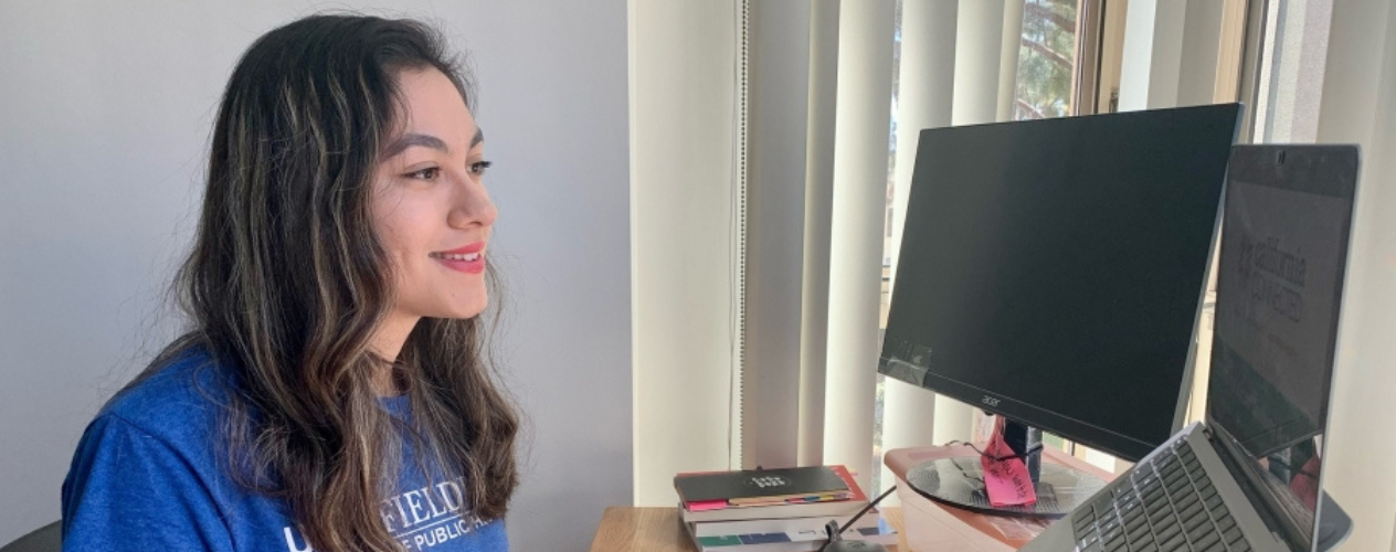 student at desk facing computer monitor