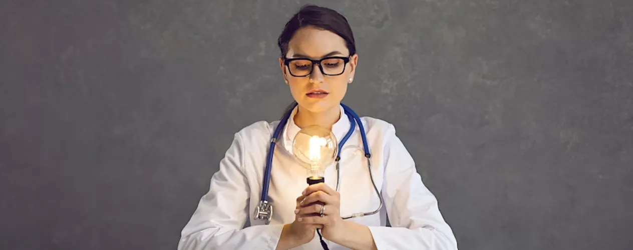 person holding light bulb wearing doctor's coat