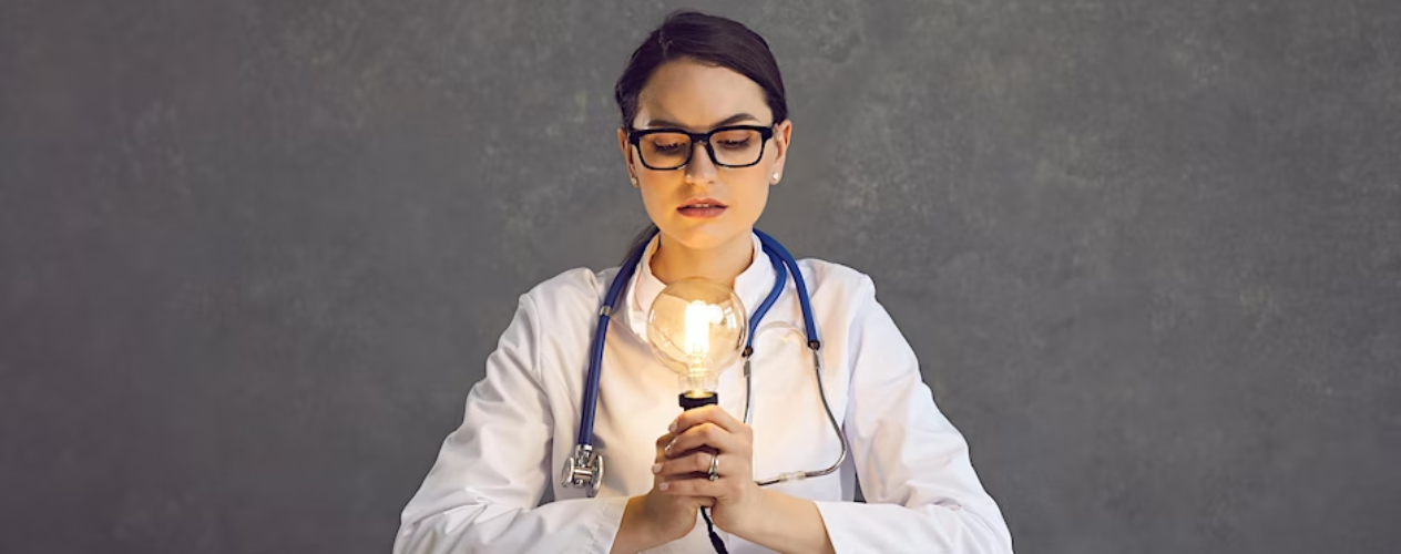 person holding light bulb wearing doctor's coat