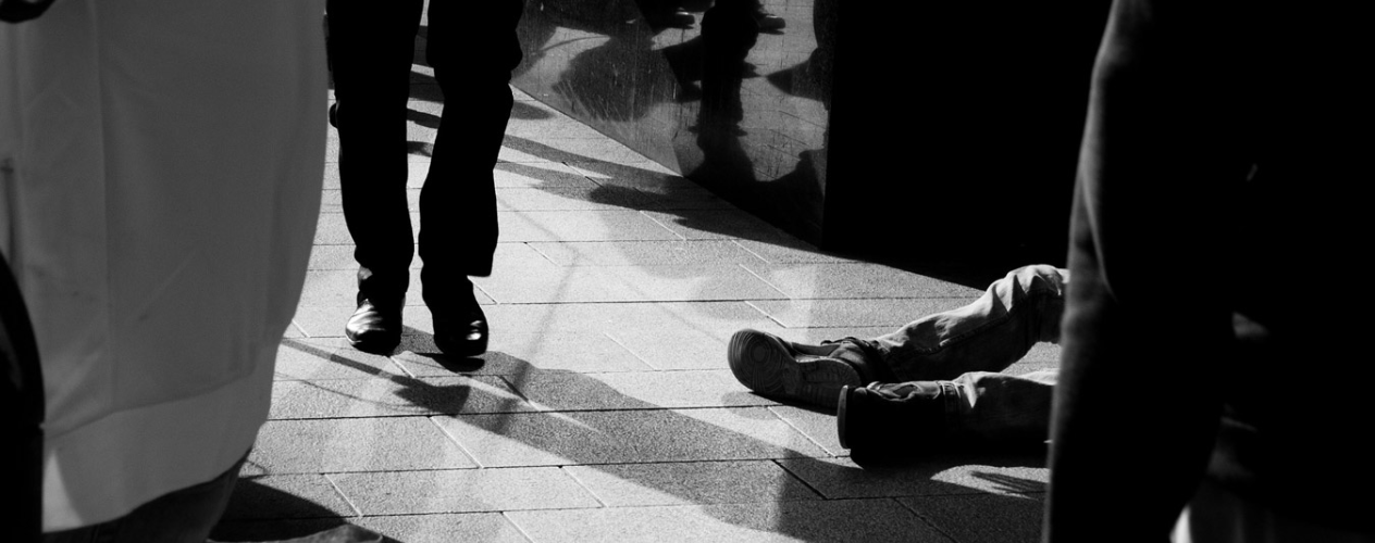Black and white photo of homeless man's feet and other walking feet