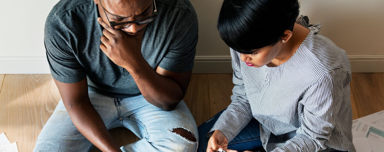 couple sitting on the floor looking at bills