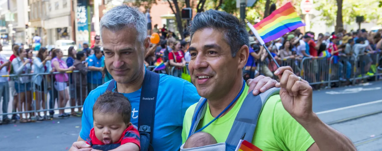 two men and a baby holding pride flags