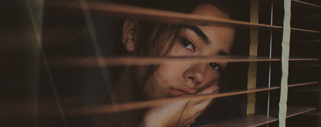 teenager behind window blinds