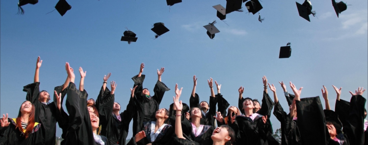 graduating students throwing caps into air