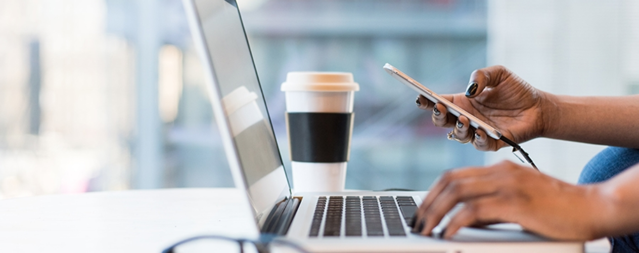 laptop, coffee cup, and phone on a desk