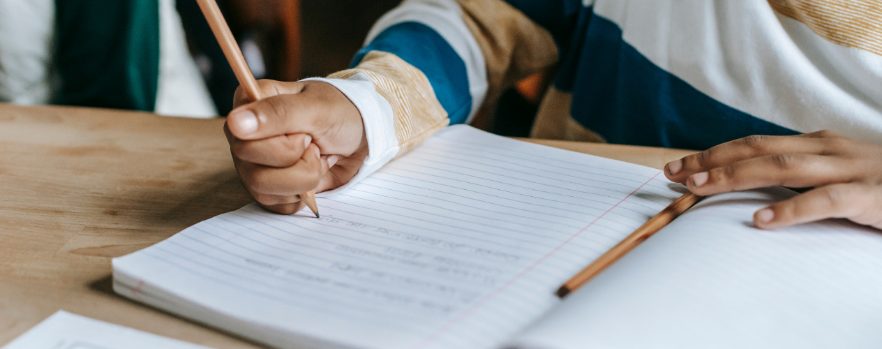 child writing in notebook in school