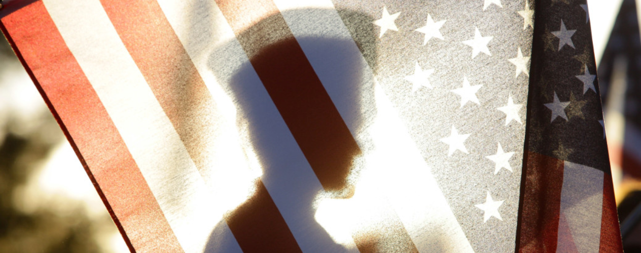 outline of veteran behind the US flag