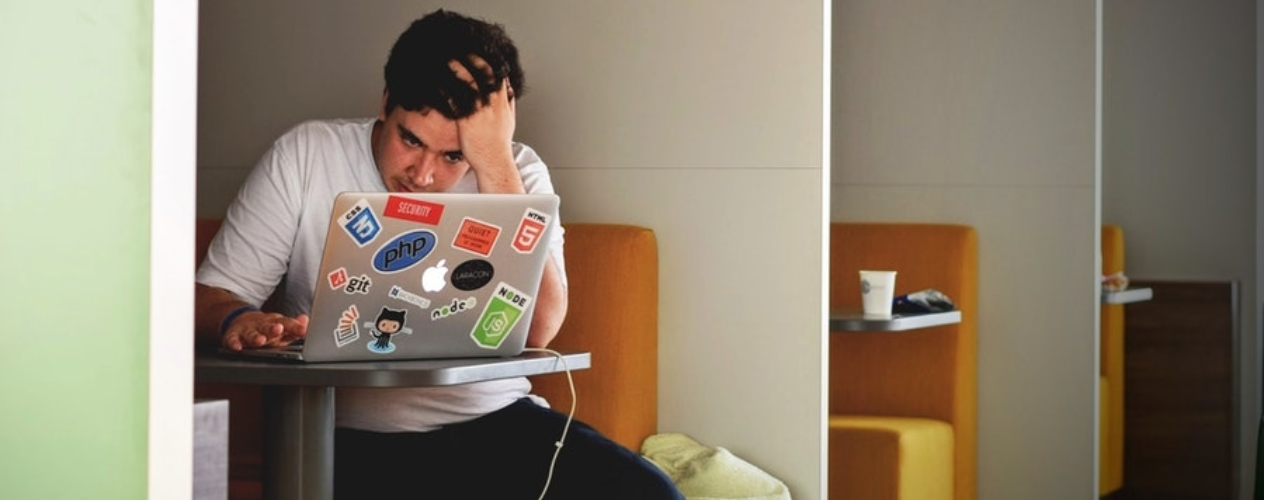 person with head in hands looking at computer