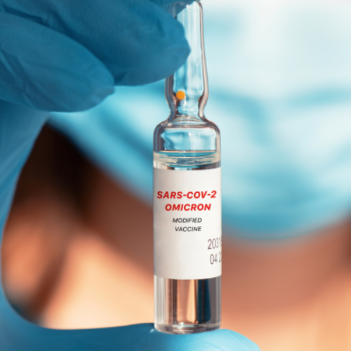 Gloved hand holding vial labeled "SARS-COV-2 OMICRON"