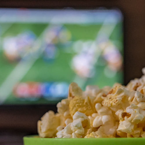Bowl of popcorn in front of TV playing football