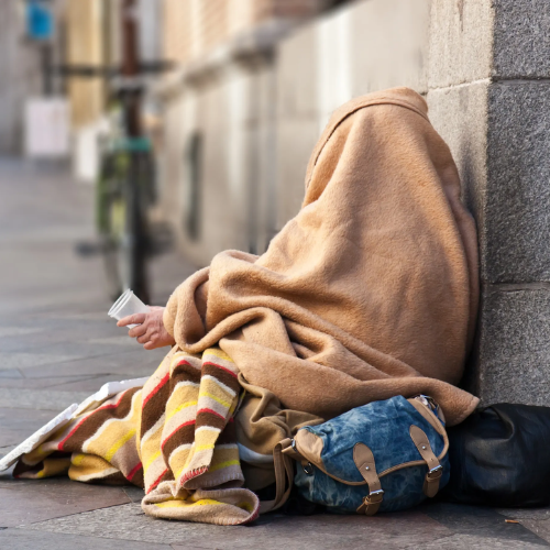 Unhoused individual wrapped in blankets
