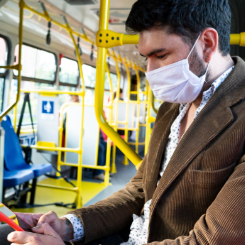 Man in mask on subway looking at phone