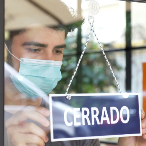 Person closing a shop with a "CERRADO" sign