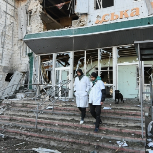 Two workers walking out of a damaged hospital in Ukraine