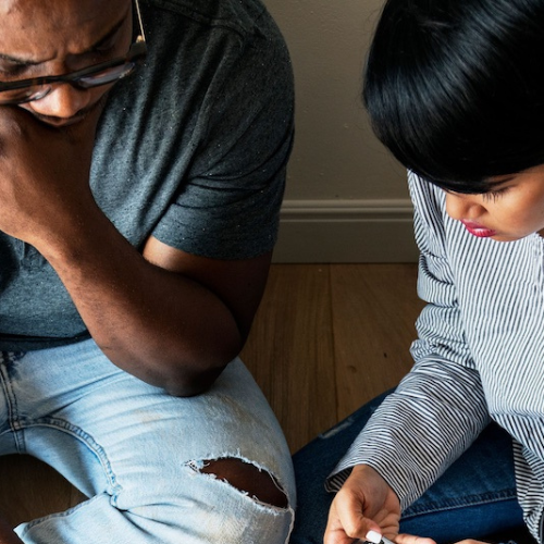 couple sitting on the floor looking at bills