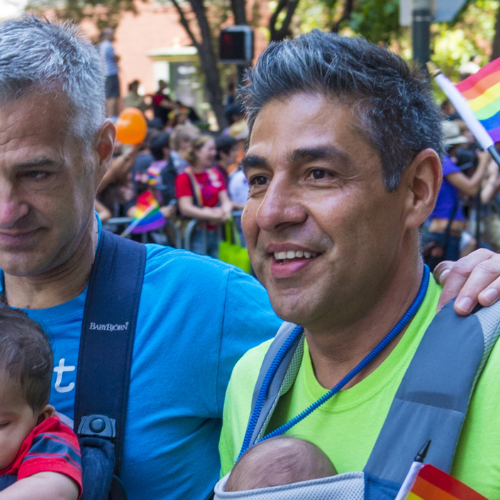 two men and a baby holding pride flags