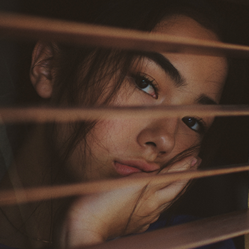 teenager behind window blinds