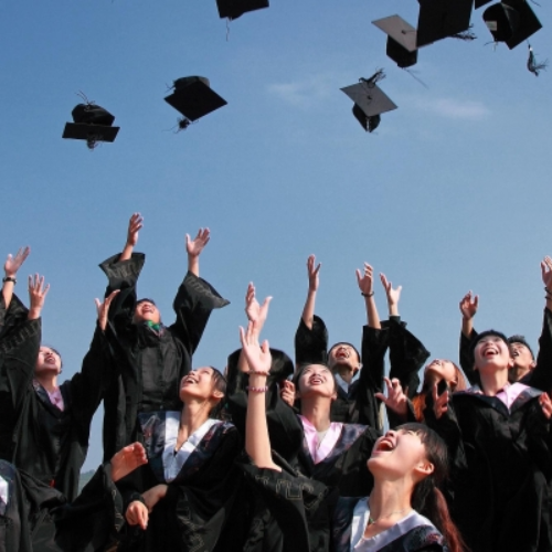 graduating students throwing caps into air