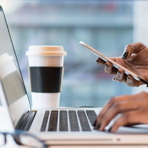 laptop, coffee cup, and phone on a desk