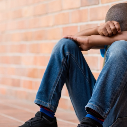 boy sitting against brick wall