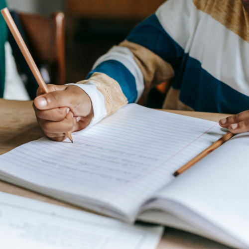 child writing in notebook in school