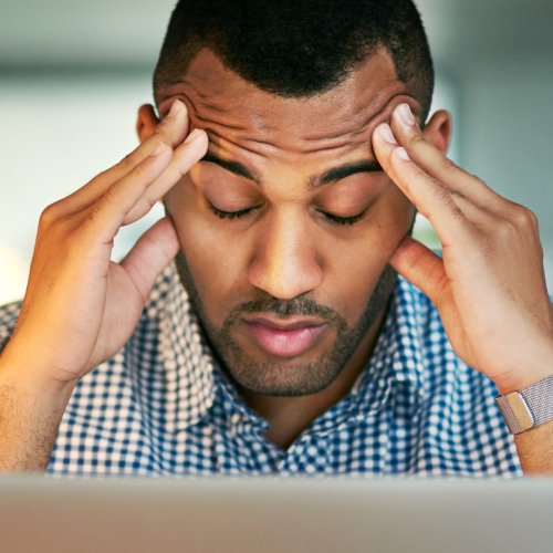 man holding his hands to his head in front of laptop