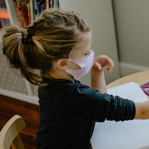 young child in mask coloring