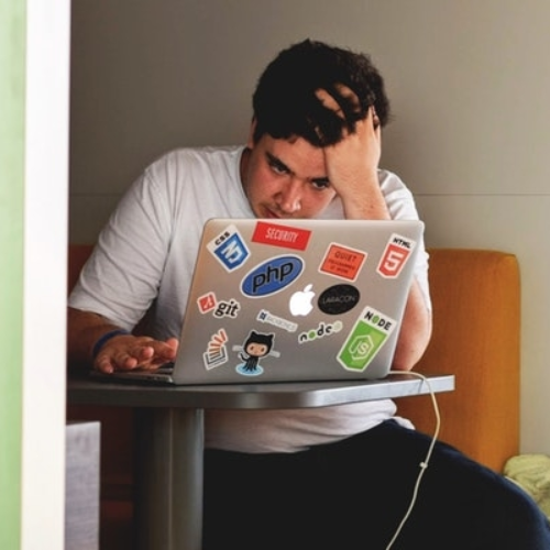 person with head in hands looking at computer