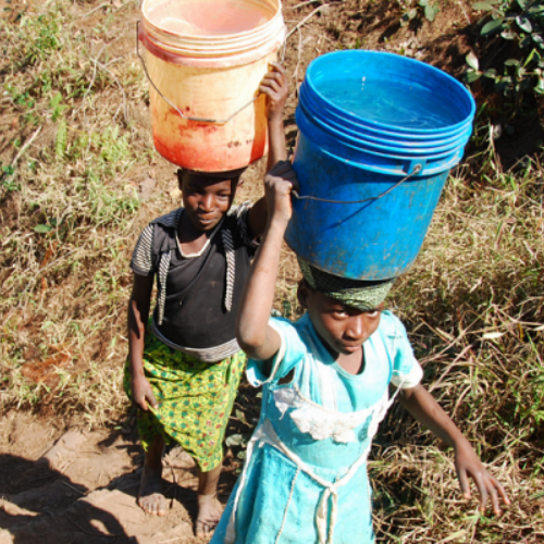 two children with buckets of water balanced on head