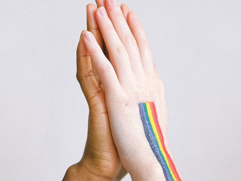 Hands praying with rainbow painted on them