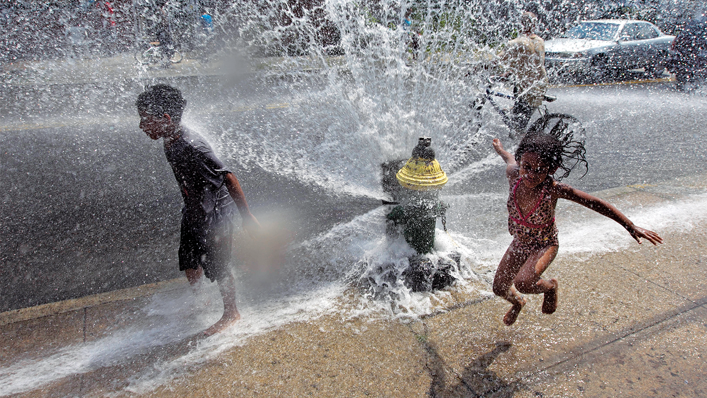 Three children playing in a sprinkler